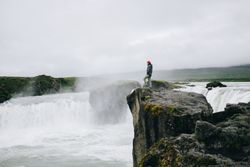 Man on cliff over waterfall, landscape
