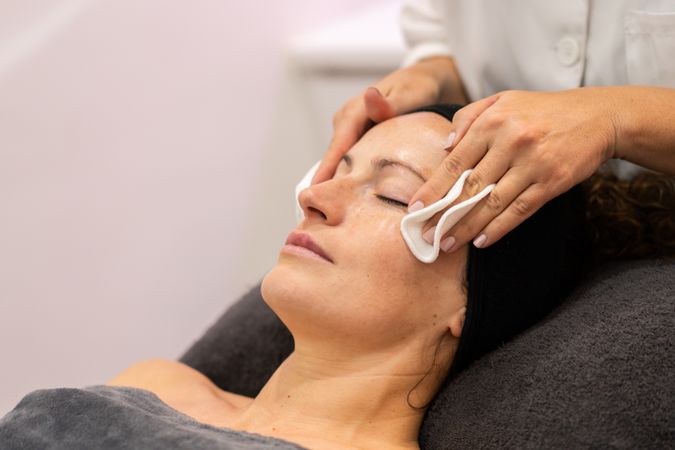 Woman having face cleansed during facial