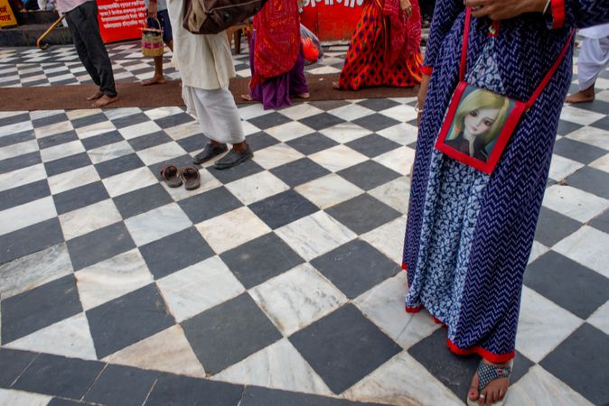 Downward angle of a woman’s dress and purse against a checkered tile floor in Rishikesh, India