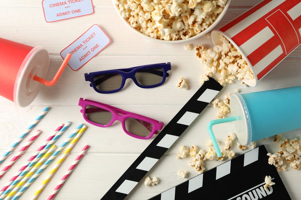 Flat lay. 3d glasses, buckets with popcorn, tickets, clapperboard, drink, on wood background
