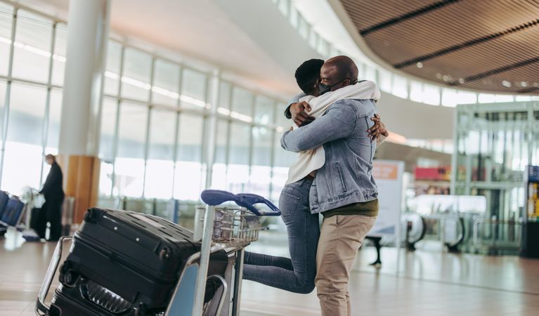 Black man meeting woman arriving at airport