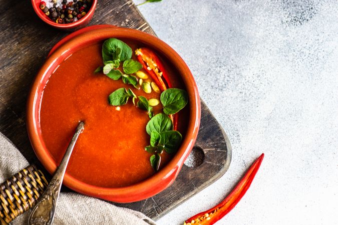 Top view of tomato soup in ceramic bowl on wooden board