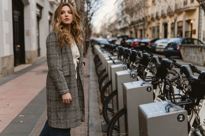 Woman choosing rental bicycle on parking lot