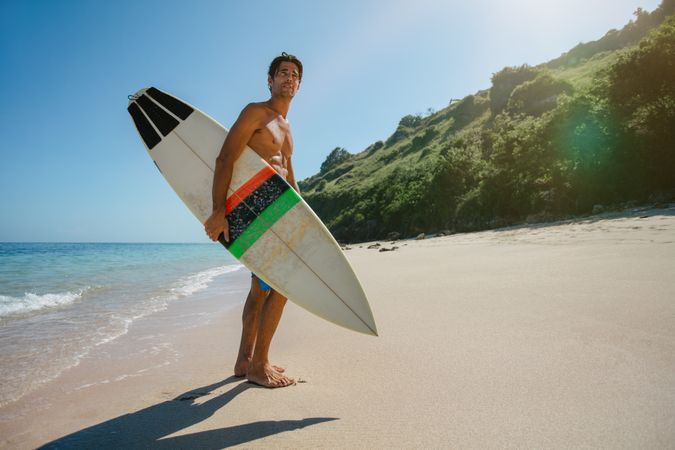 Surfer holding a surf board on beach