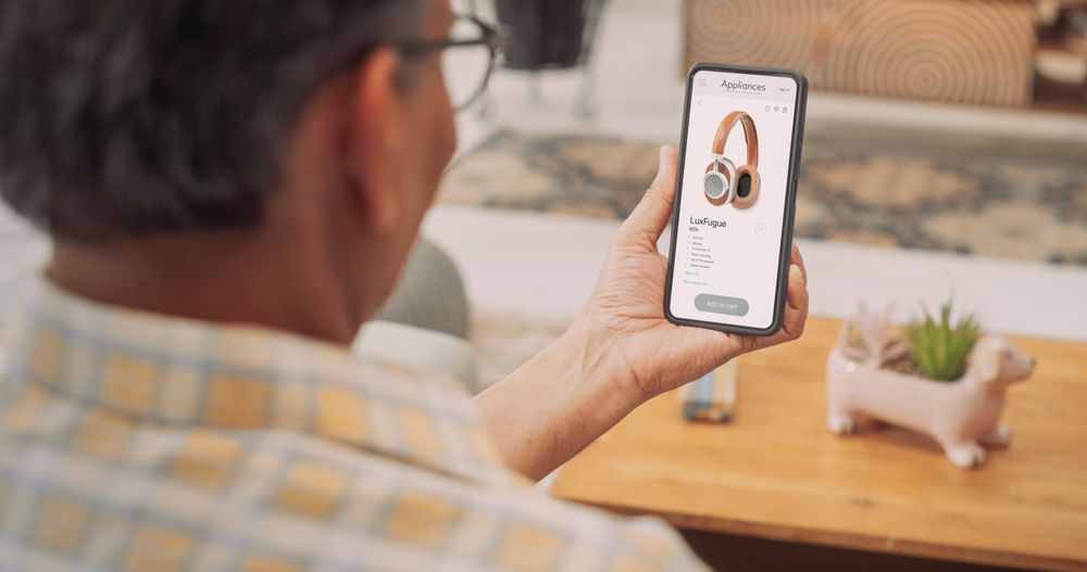 Over-the-Shoulder View of Mature Indian Gentleman Using Smartphone to Buy Headphones