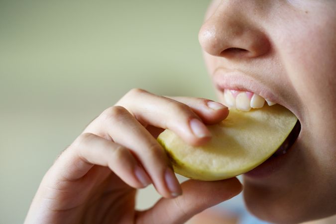 Teenage girl eating slice of apple