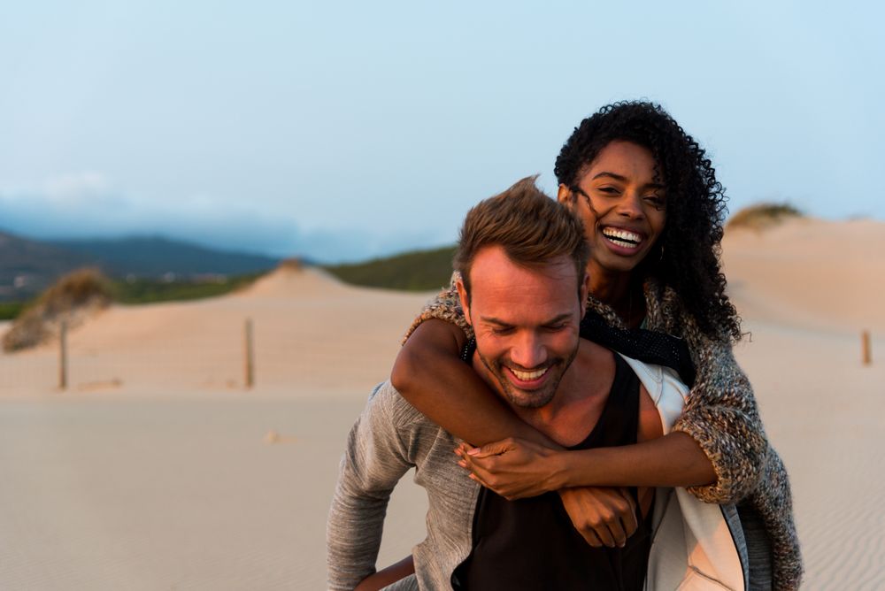 Couple doing piggyback having fun at beach