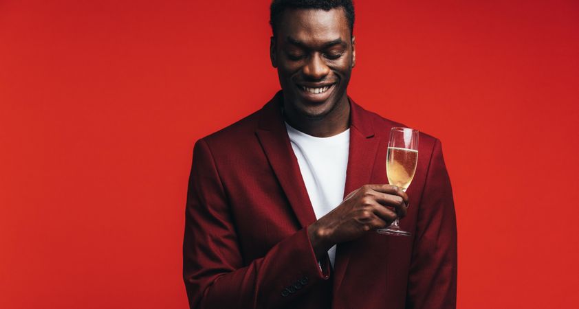 Relaxed young man with a glass of champagne and thinking against colored background