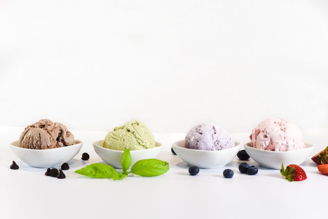 Side view of four small bowls of colorful ice cream
