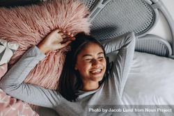 Young woman lying on bed with eyes closed and laughing 5oqE8b