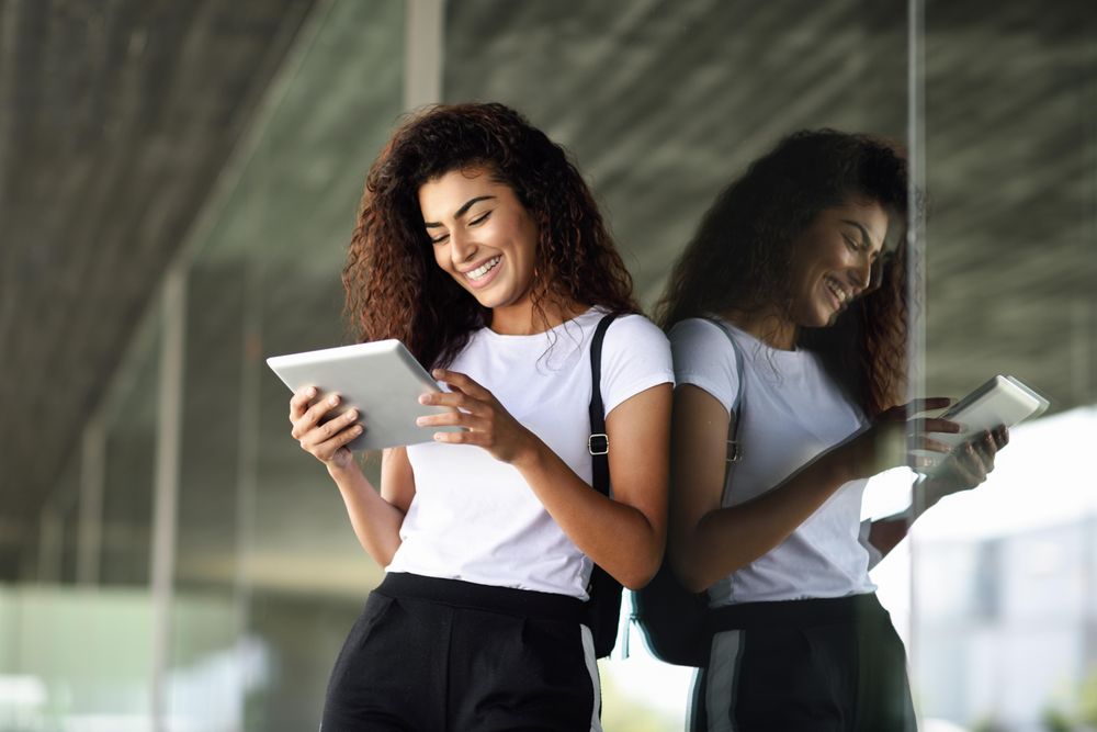 Smiling Arab woman using digital tablet in front of corporate office building