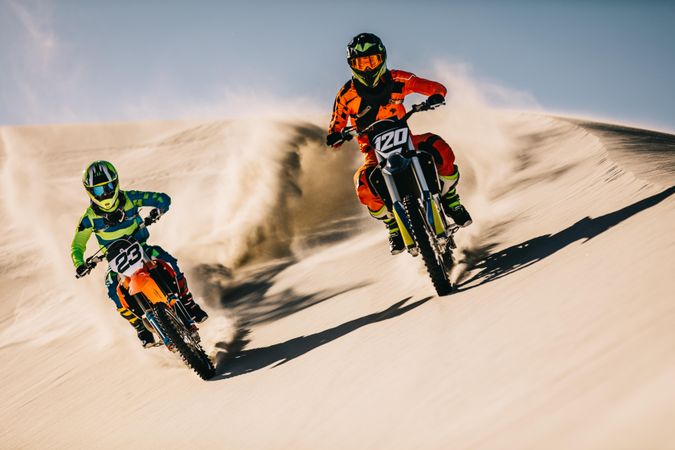 Motocross bikes doing full speed over sand dunes