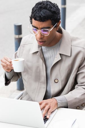 Focused man using laptop and drinking coffee