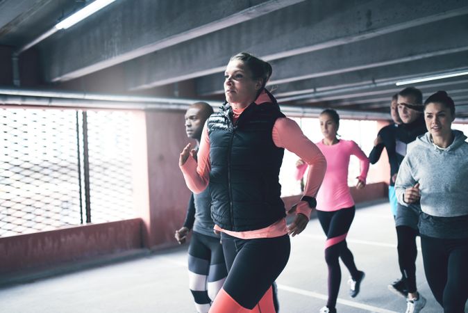 Multi ethnic group of people running in car garage