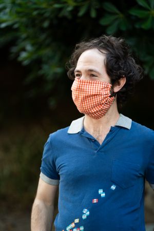 Portrait of man in PPE mask smiling and looking away outside in garden
