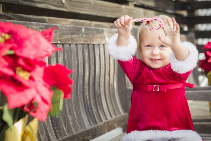 Adorable Little Girl Sitting On Bench with Her Candy Cane