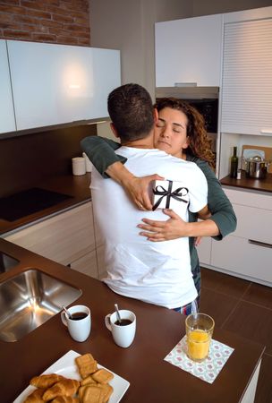 Couple hugging over breakfast at home before work with giftbox