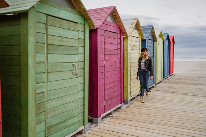 Woman walking throughout wooden cabins on beach
