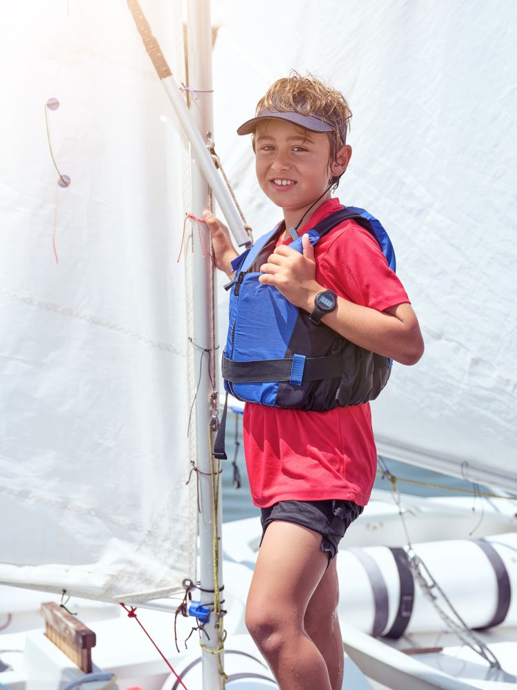 Smiling boy standing on sailboat