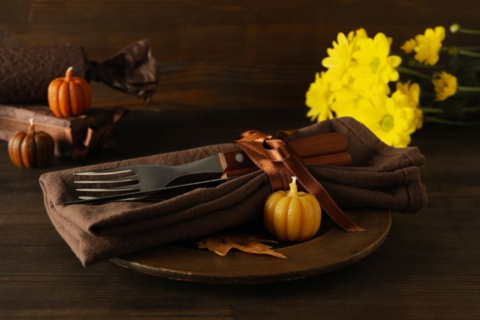 Cutlery on plate, pumpkins and flowers on wooden background