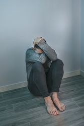 Unrecognizable man with problems sitting on floor