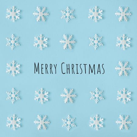 Snowflakes arranged on blue background with “Merry Christmas”