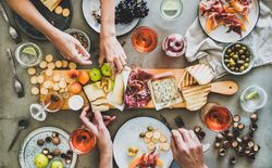 Charcuterie board with hands reaching for cheese and fig