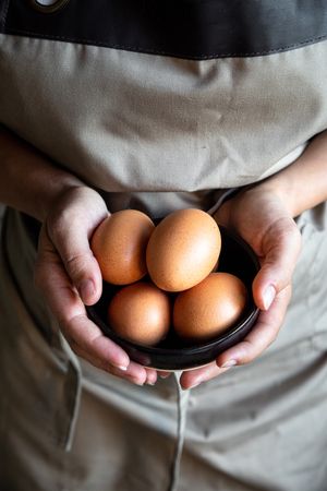 Faceless person holding bowl with eggs