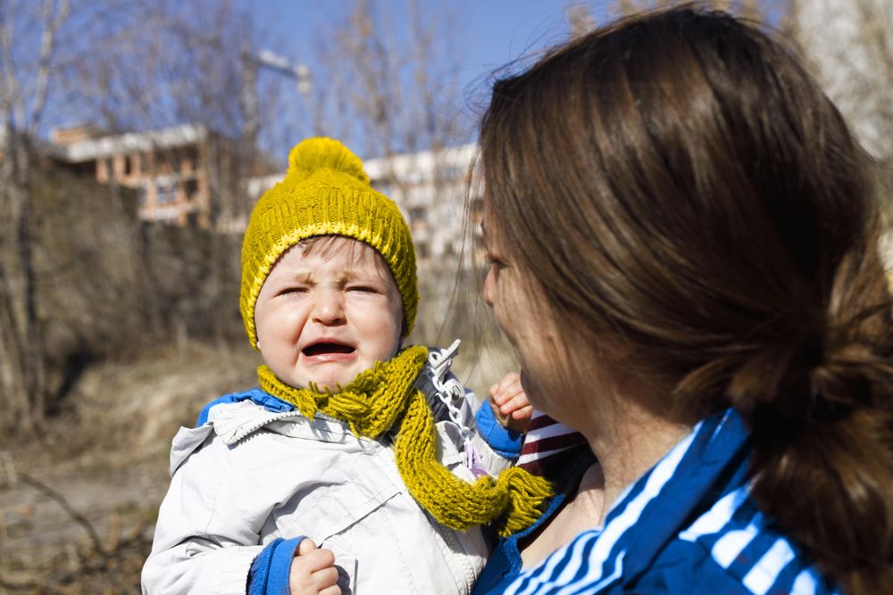 Woman standing with her crying child outside