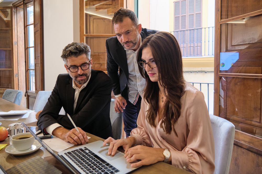 Focused colleagues working on laptop together
