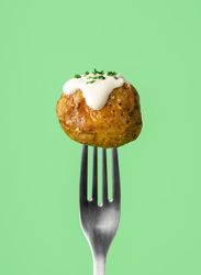 Single roasted potato with sour cream sauce drip on a fork