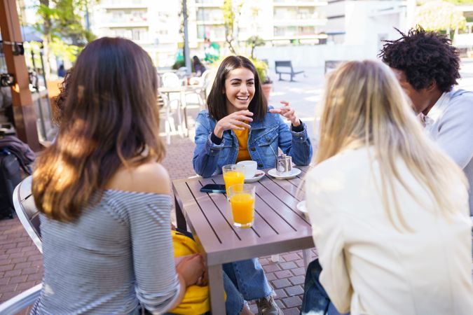 Woman smiling and laughing her friends at an outside table