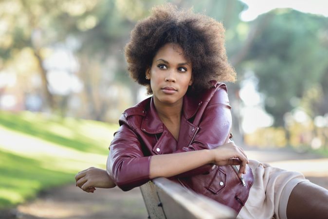 Contemplative woman sitting outside in red leather jacket looking to the side