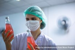 Woman worker inspecting on juice bottle at factory 0VDEj4