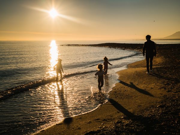 Anonymous father walking with children at sunset