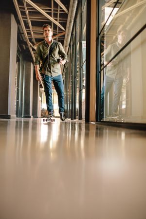 Casual businessman skating through office corridor