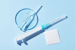 Needle and disinfectant pad on blue background