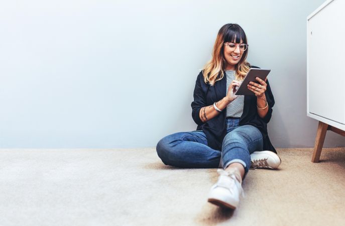 Smiling woman sitting on floor using a tablet pc
