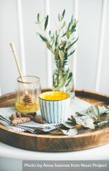 Wood tray with latte coffee, honey dipper, and vase with olive leaves 5kavWb
