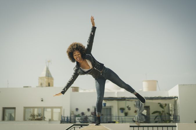 Funny Black woman balancing on wall
