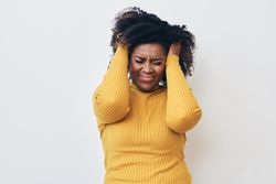 Woman with hand in hair struggling through headache