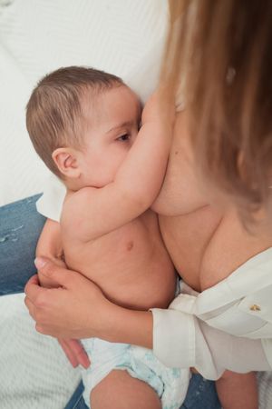 mother breast feeding and hugging baby