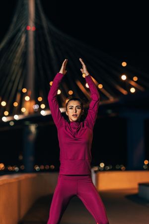 Female athlete in front of bridge at night