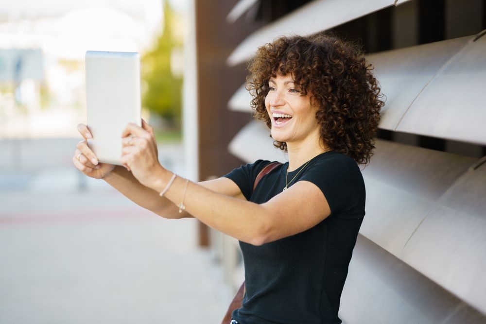 A Joyful Young Woman Taking a Vibrant Selfie Outdoors in a Beautiful Natural Setting