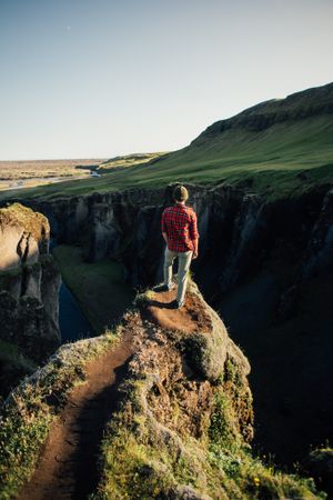 Young man standing on edge of cliff