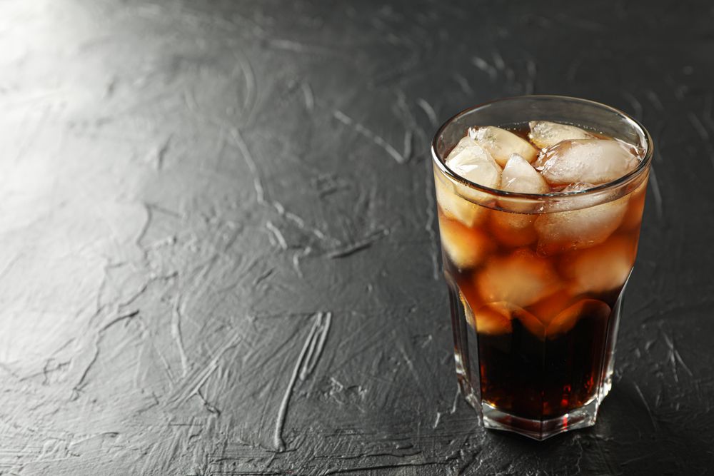 Glass of cold cola on cement background