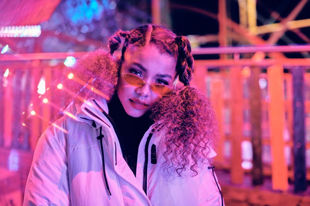 Young woman wearing red sunglasses beneath red light