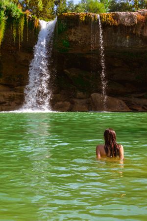 Anonymous female standing near amazing waterfall