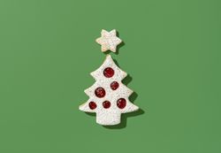 Christmas tree shaped cookie on a green background, top view
