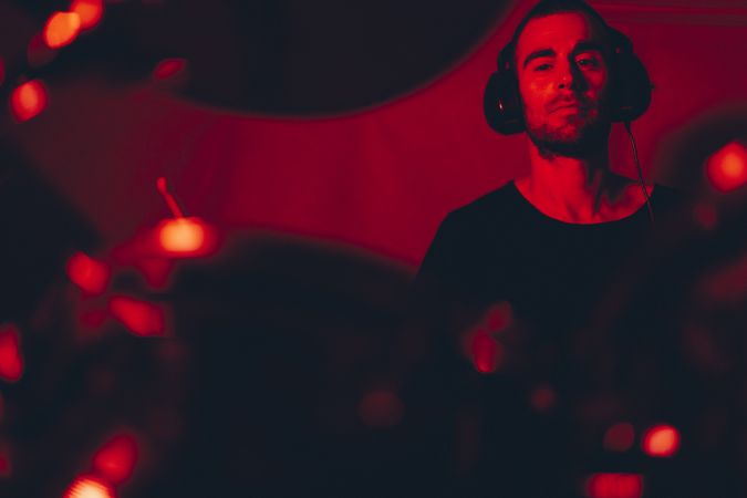 Man with drumsticks playing on drums in redness